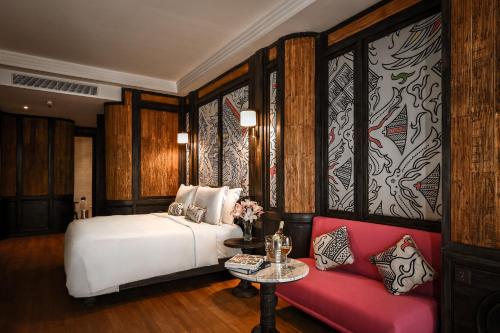 a bedroom with a white bed and a red couch at The Orient Jakarta, a Royal Hideaway Hotel in Jakarta