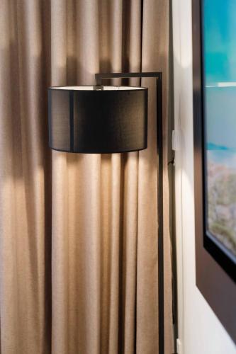 a lamp in a room next to a curtain at Hotel Soleil Ha Long, Trademark Collection by Wyndham in Ha Long