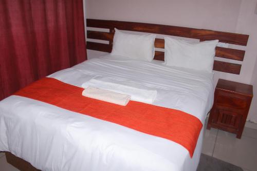 a large bed with a red and white blanket at Universe GuestHouse in Kasane