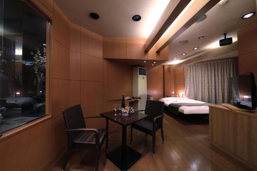 四日市市にあるホテルミオプラザ(大人専用)のベッド、テーブル、椅子が備わるホテルルームです。