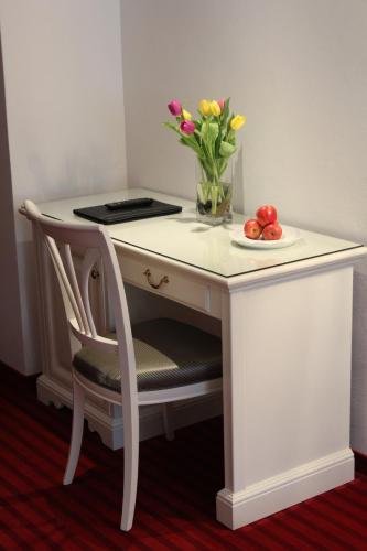 a white desk with a vase of flowers and a plate of fruit at Seilers Vintage Hotel & Spa in Kandersteg
