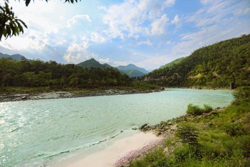 a river in the mountains with a beach at Anand Kashi by the Ganges Rishikesh - IHCL Seleqtions in Rishīkesh