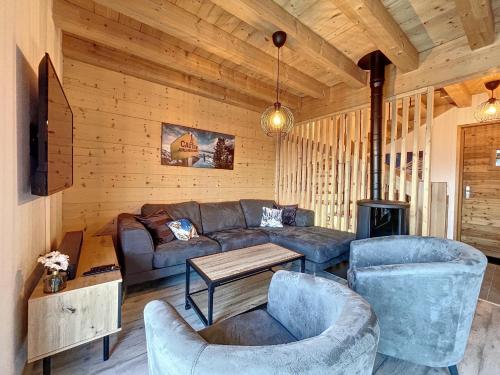 ein Wohnzimmer mit einem Sofa, Stühlen und einem Tisch in der Unterkunft Chalet Le Vallonnet in La Toussuire