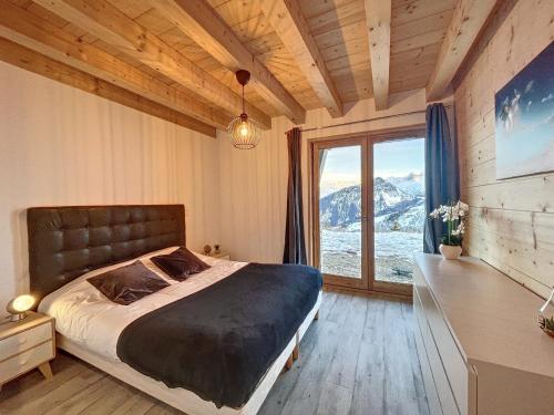 a bedroom with a bed and a large window at Chalet Le Vallonnet in La Toussuire