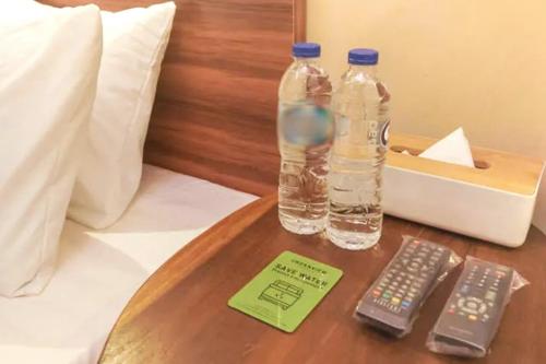 zwei Flaschen Wasser und eine Fernbedienung auf dem Tisch in der Unterkunft Urbanview Grand Lotus Hotel by RedDoorz in Purwokerto