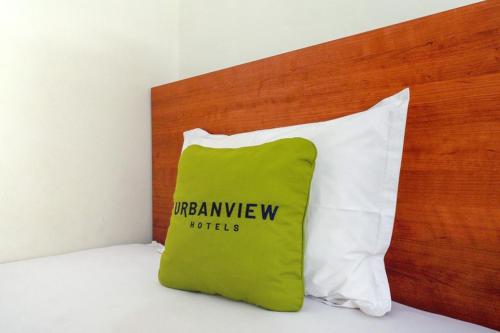 ein grün-weißes Kissen auf einem Bett in der Unterkunft Urbanview Grand Lotus Hotel by RedDoorz in Purwokerto