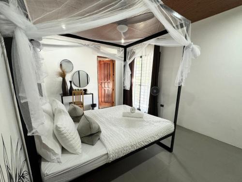 a bedroom with a canopy bed with white sheets and pillows at Mahajab Homestay SIARGAO in General Luna