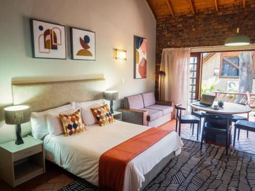 a bedroom with a bed and a table and a chair at Olifants River Lodge by Dream Resorts in Middelburg