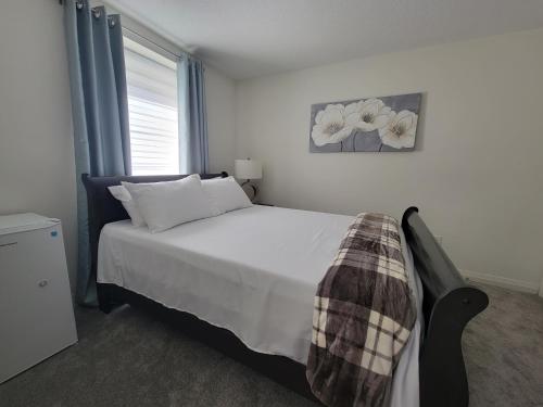 una camera da letto con un letto con lenzuola bianche e una finestra di Chorburjo Cozy Villa - Deluxe Room a Penetanguishene