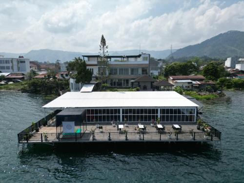 a building on a dock in the water at PURNAMA BALIGE HOTEL in Balige