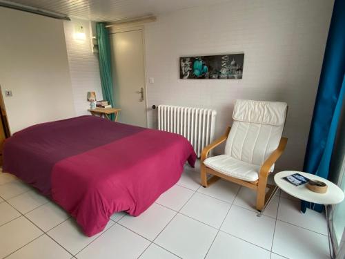 a bedroom with a bed and a chair and a table at Studio dans maison avec parking in Bouguenais