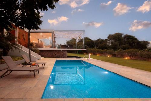 una piscina en un patio trasero con una meta en Open House by StayVista - Nestled in nature, featuring a Swimming pool & Expansive lawn for a serene retreat, en Shikrapur