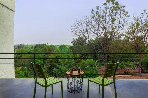 two chairs and a table on a balcony at Open House by StayVista - Nestled in nature, featuring a Swimming pool & Expansive lawn for a serene retreat in Shikrapur