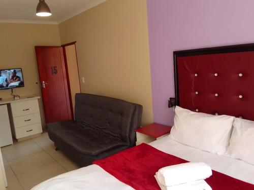 a hotel room with a bed and a chair at Emampingeni lodge in Bizana