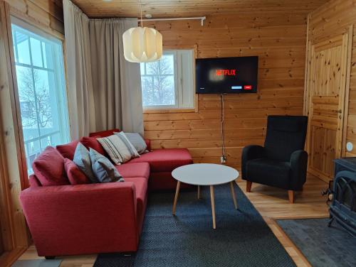 a living room with a red couch and a tv at Twin Peaks Urupää B Saariselkä in Saariselka