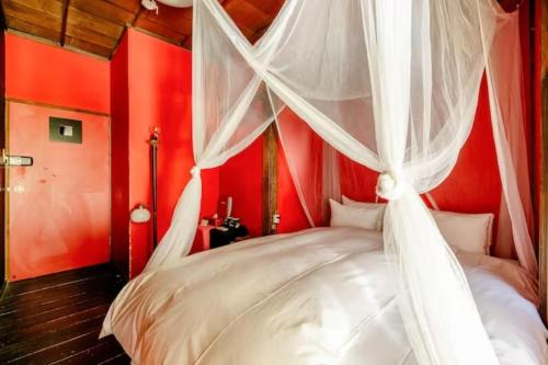 a red bedroom with a canopy bed with white curtains at Villa Sacra in Kamakura