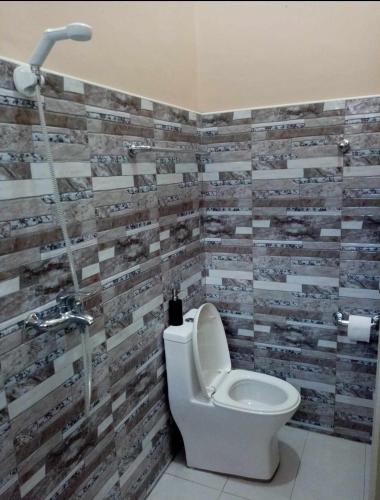 a bathroom with a toilet and a tile wall at Malibu Homes in Casisang