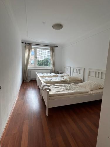two beds in a white room with a window at City-Charme: 5 Gäste,Top-Lage in Hannover