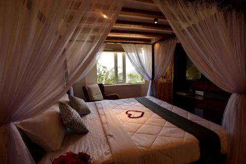 a bedroom with a bed with curtains and a window at Green Wood Hill Cottage in Ooty