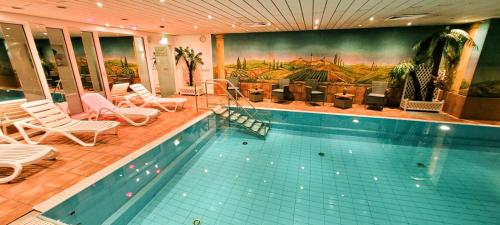 einen Pool mit Stühlen und ein Gemälde an der Wand in der Unterkunft Morada Hotel Gothaer Hof in Gotha