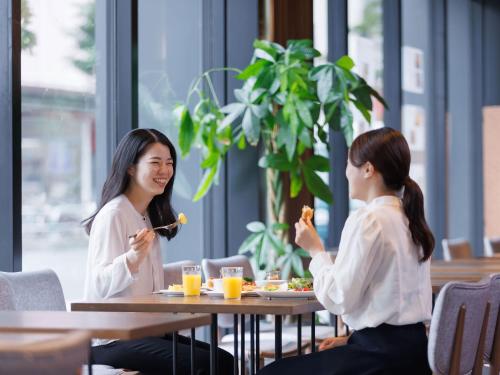 two women sitting at a table eating food at Susukino Granbell Hotel in Sapporo