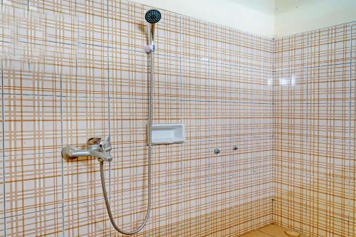 a shower in a tiled bathroom with a shower head at OYO 92217 Artana Bed and Breakfast in Pengalongan