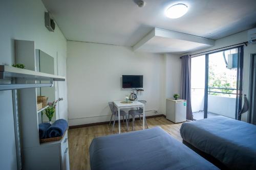 a bedroom with two beds and a table and a window at Baansuay Rattanathibet Apartment in Nonthaburi