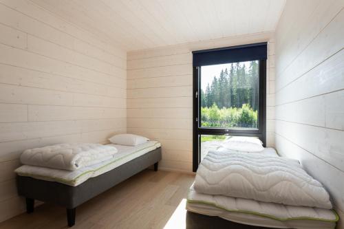 two beds in a room with a window at Himoskuutio 8, erillistalo, ulkoporeallas in Jämsä