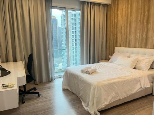 a bedroom with a bed and a desk and a window at MyRehat Suites Bukit Ceylon in Kuala Lumpur