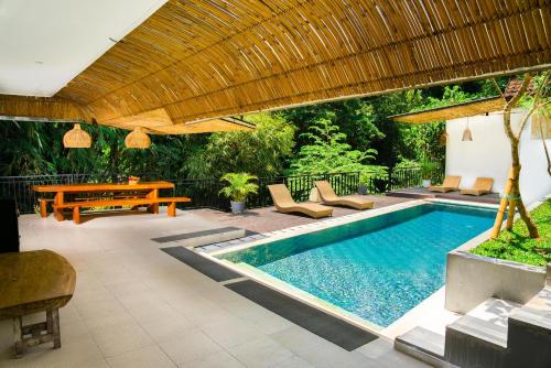 a swimming pool with a table and chairs and a patio at Bali Invest Living in Canggu