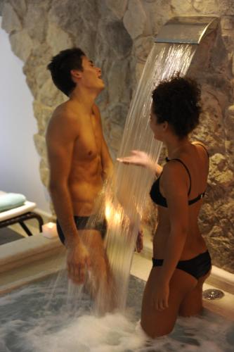a man and woman standing in a hot tub with a waterfall at Parc Hotel Flora S in Riva del Garda