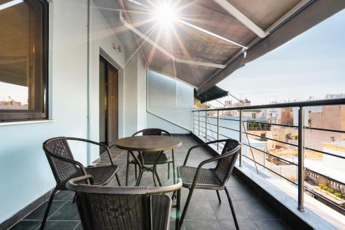 a table and chairs on a balcony with a view at Sanders Home Suites in Athens