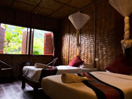 a bedroom with two beds and two windows at Mekong Riverside Lodge in Pakbeng