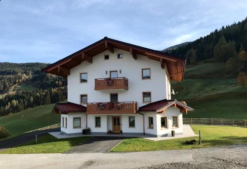 a large white house with a balcony on a hill at Bio Schartenhof in Sankt Johann im Pongau