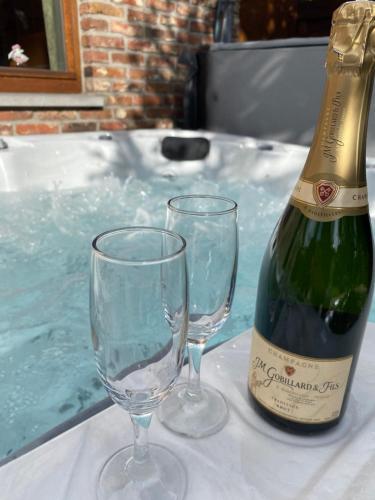 a bottle of wine and two wine glasses on a table at Le Logis du Plateau in Herve