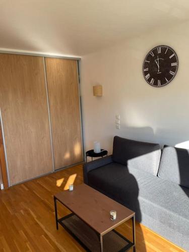 un salon avec un canapé et une horloge au mur dans l'établissement Studio Gentilly/Paris 14, à Gentilly