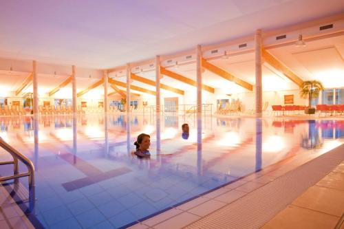 2 niños nadando en una gran piscina en Morada Strandhotel Ostseebad Kühlungsborn, en Kühlungsborn