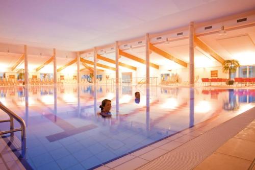 two children swimming in a large swimming pool at Morada Strandhotel Ostseebad Kühlungsborn in Kühlungsborn