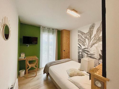サン・タンドレ・レ・ザルプにあるHôtel Le Bel Airの緑の壁のベッドルーム(ベッド1台、テレビ付)