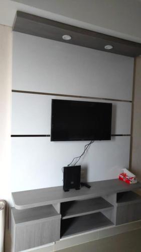 TV de pantalla plana en una pared blanca en Apartemen Skylounge Makassar en Manda