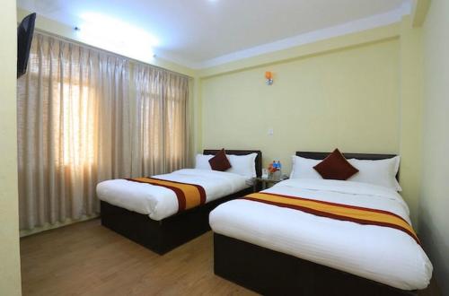 een hotelkamer met 2 bedden en een raam bij Hotel Bihani in Dhulikhel