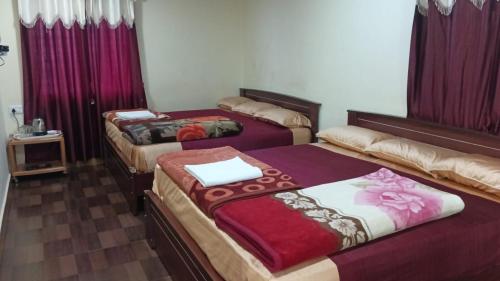 three beds in a room with purple curtains at Green Star Bungalow in Kodaikānāl