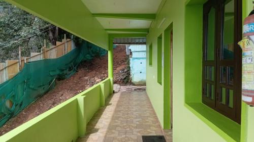 un couloir d'un bâtiment avec des murs verts et une porte dans l'établissement Green Star Bungalow, à Kodaikānāl