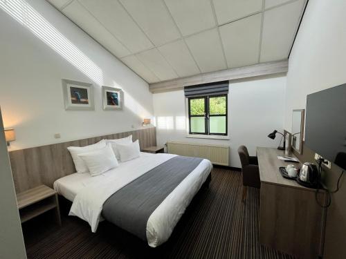 ウフストヘーストにあるLandgoed Oud Poelgeest - Leidenの大きなベッドとデスクが備わるホテルルームです。