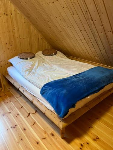 a bed in a room with a wooden floor at Domek całoroczny HAWAJE nad jeziorem Kazub in Cieciorka