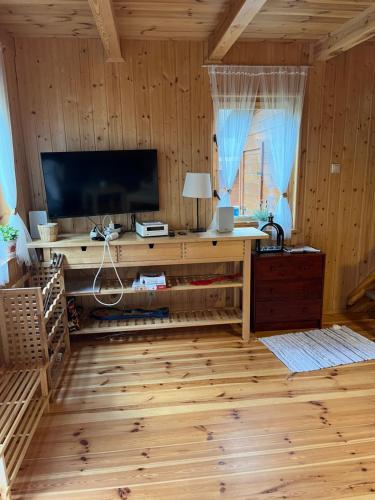 a living room with a television and a wooden floor at Domek całoroczny HAWAJE nad jeziorem Kazub in Cieciorka