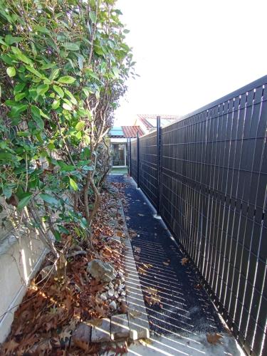 a fence next to a garden with leaves on the ground at Appart'hôtel Le Clos Lassagne à Brignais - Lyon Sud in Brignais