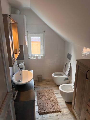 a white bathroom with a sink and a toilet at Kuća za odmor “Viola” in Vukovar