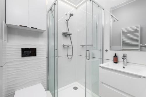 a white bathroom with a shower and a sink at Lewicka 8 by Homeprime in Warsaw