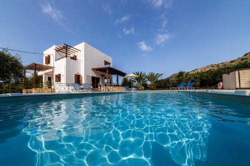 a villa with a swimming pool in front of a house at Villa Angelos with private gated pool in Almyrida